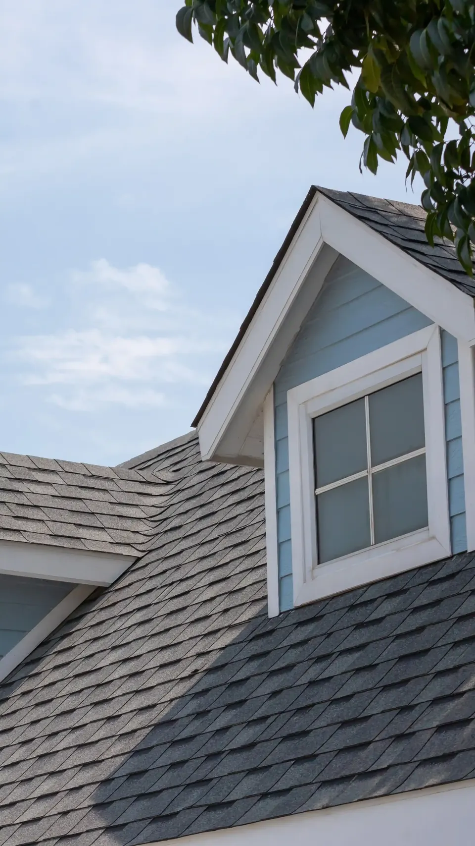 Dormer window on a roof with dark asphalt shingles
