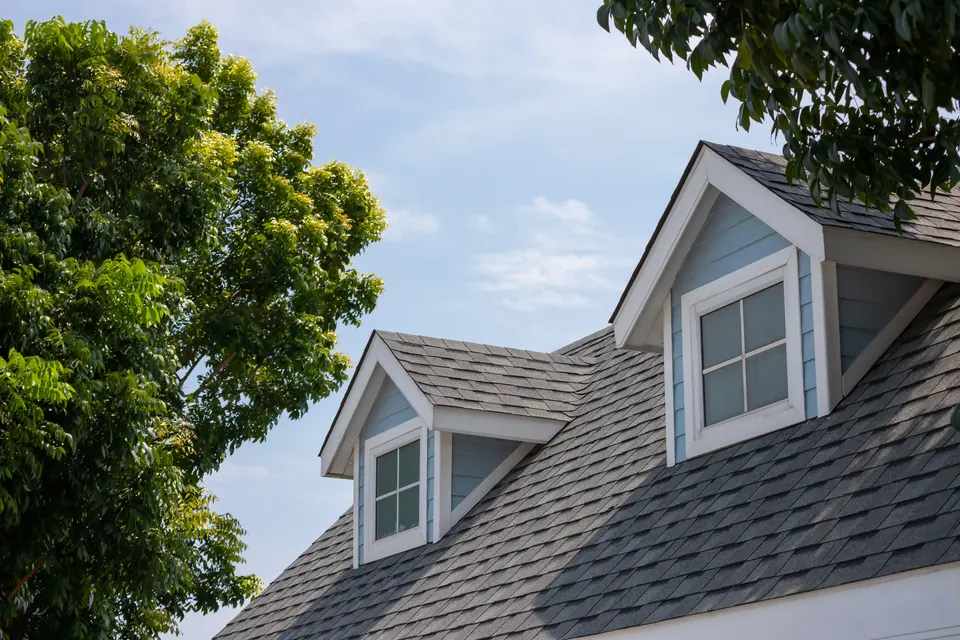 Two dormers on a house with new dark asphalt shingles