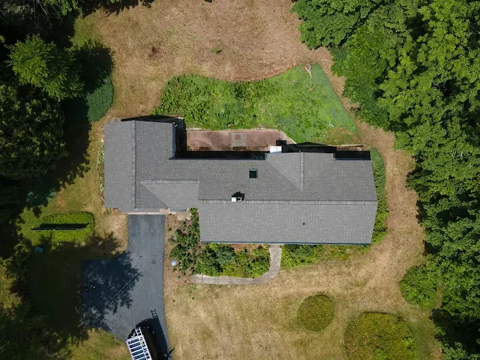 Aerial view of a finished shingle roof on a house surrounded by lawn