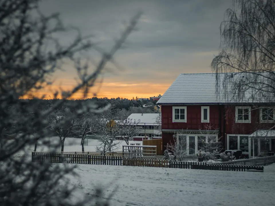 Red house with a snow-covered roof at dusk